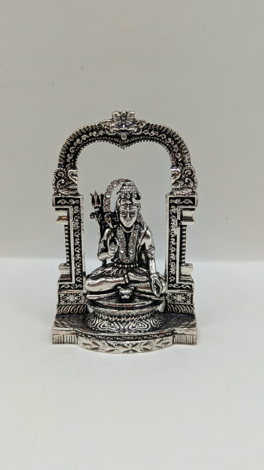 Silver sitting Shiva murti in temple arch, front view