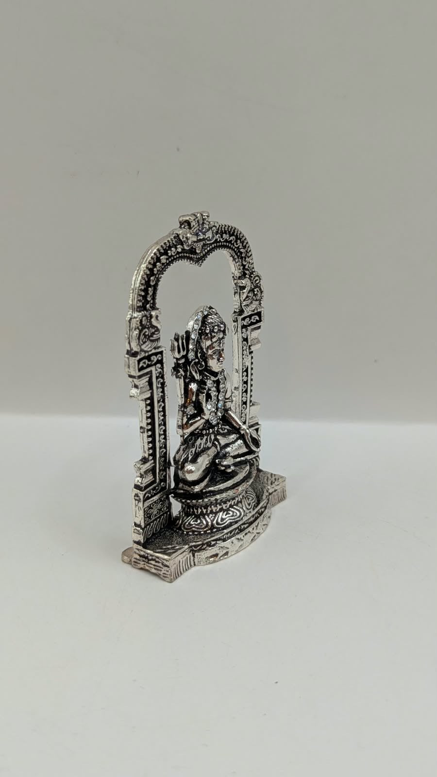 Silver sitting Shiva murti in temple arch, side view