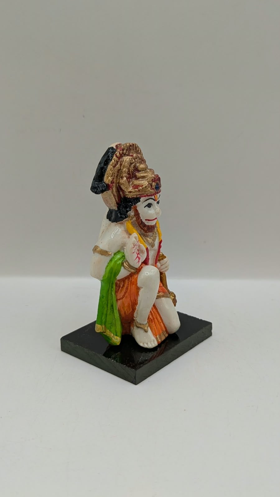 Green and orange kneeling Hanuman resin statue, side view