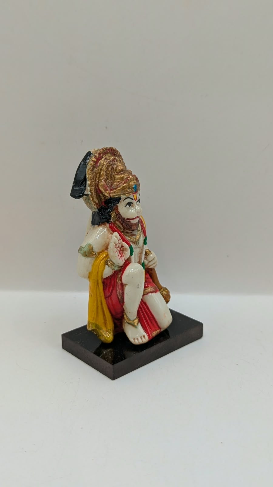Yellow and red kneeling Hanuman resin statue, side view