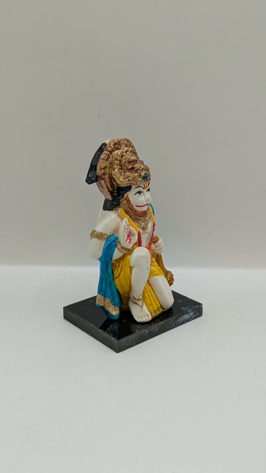 Blue and yellow kneeling Hanuman resin statue, side view