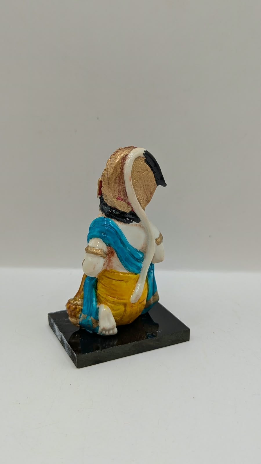 Blue and yellow kneeling Hanuman resin statue, back view