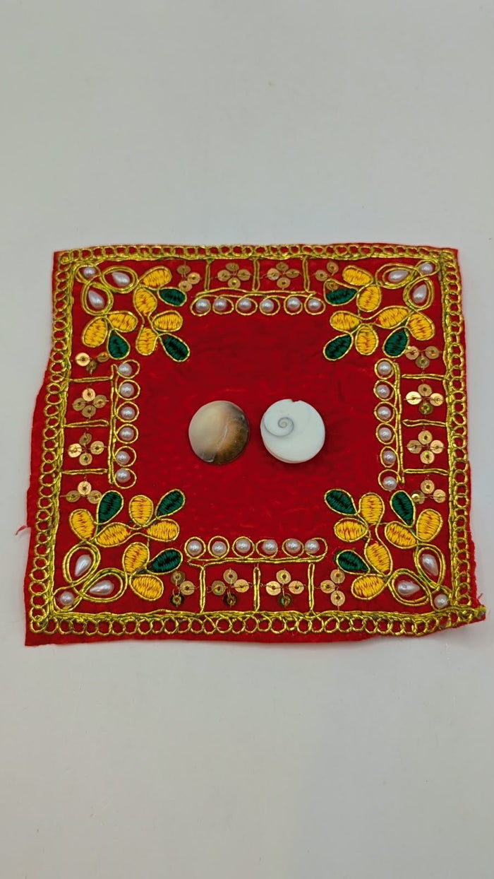 Two Gomti Chakra shells on red cloth