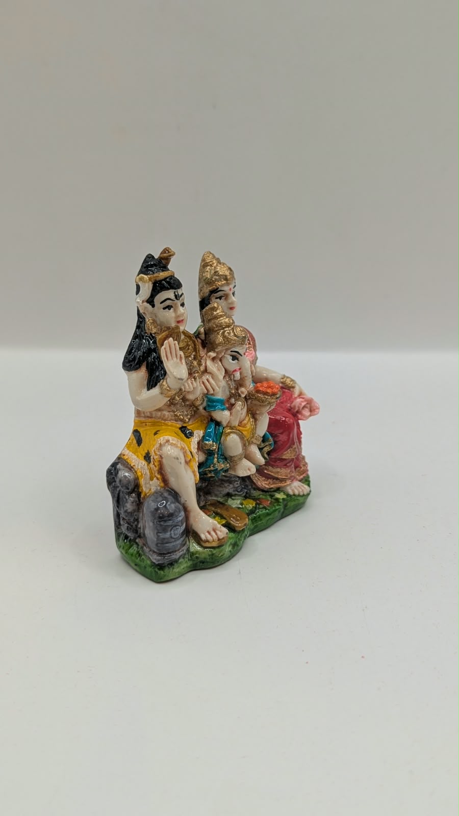 Colourful Shiv Parivar resin statue on green base, side view