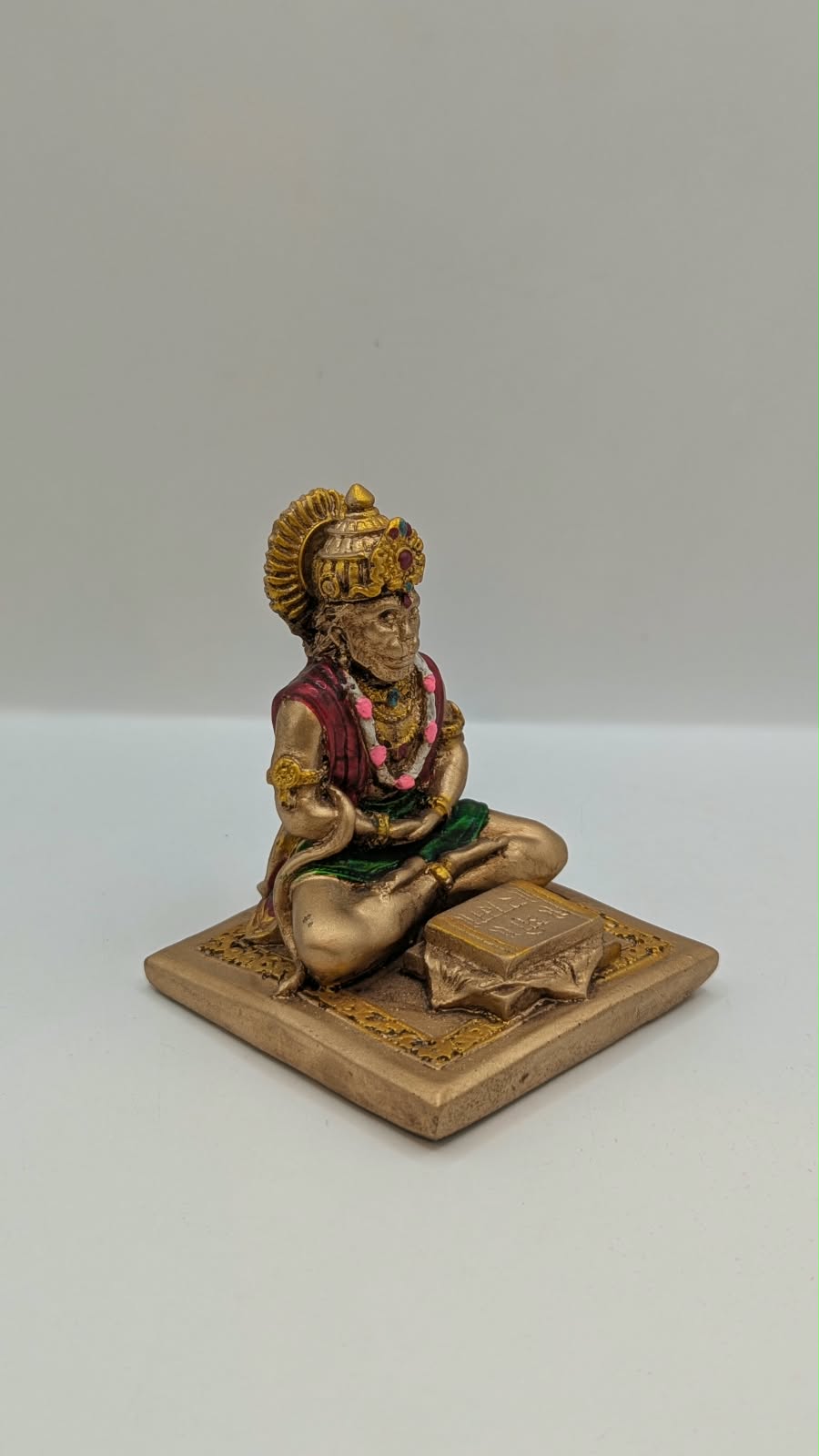 Gold and maroon Hanuman reading Ramayan resin statue, side view