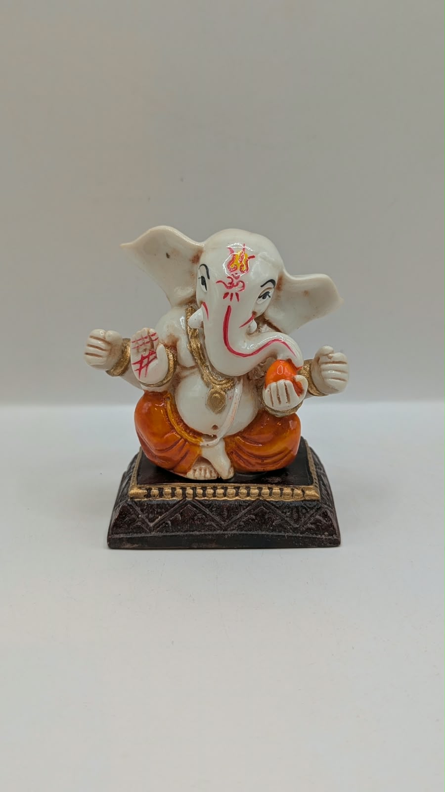 White and orange Ganesh resin statue, front view