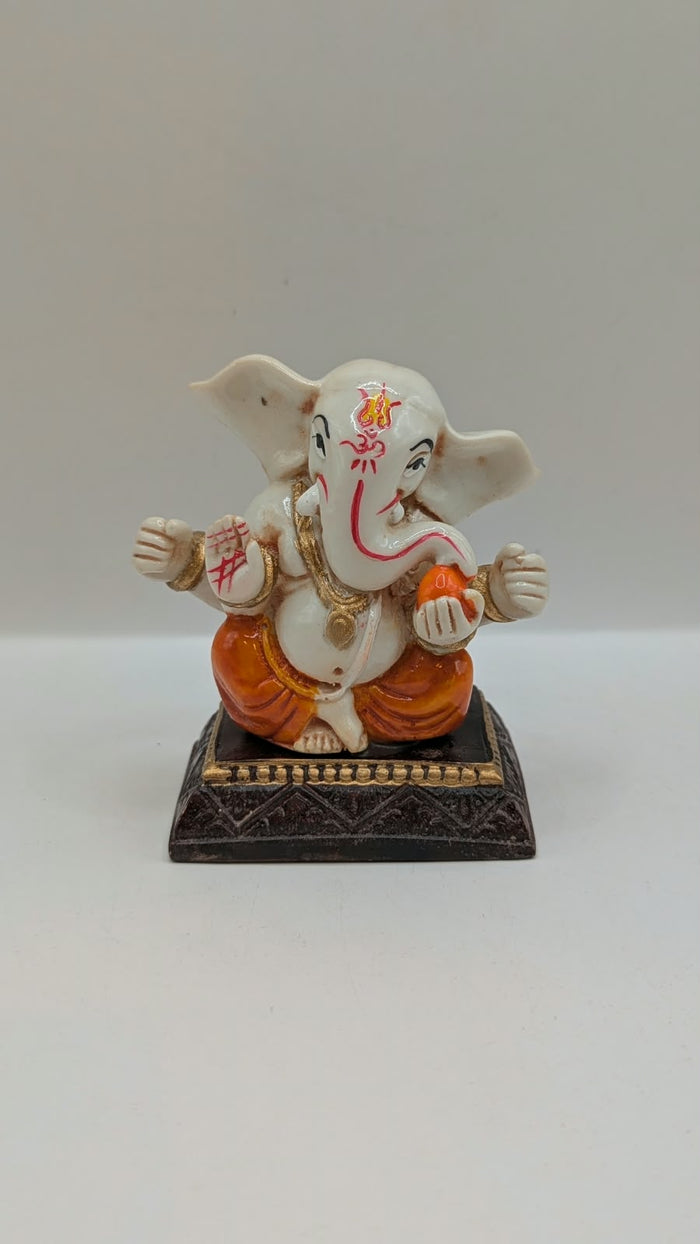 White and orange Ganesh resin statue, front view