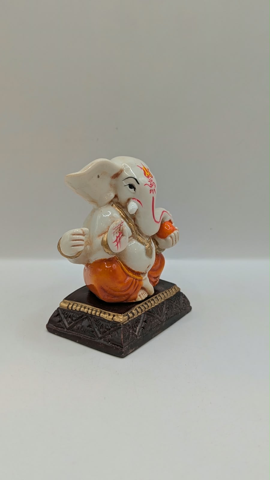 White and orange Ganesh resin statue, side view