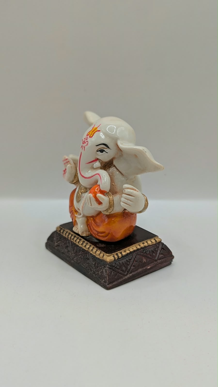 White and orange Ganesh resin statue, other side view