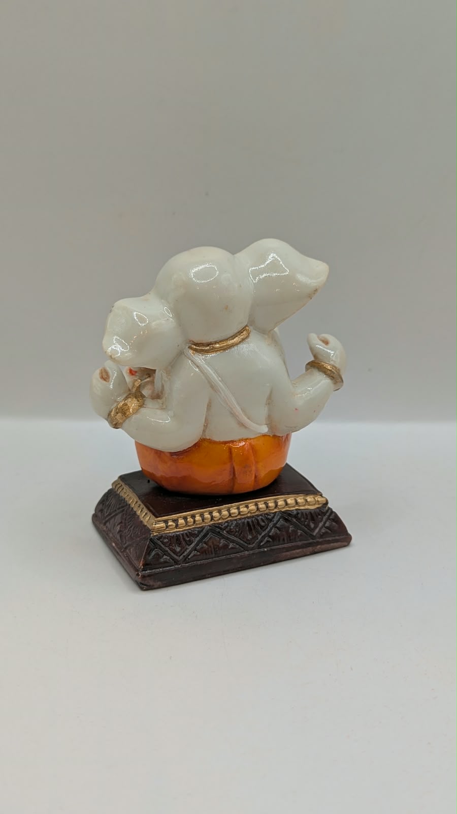 White and orange Ganesh resin statue, back view