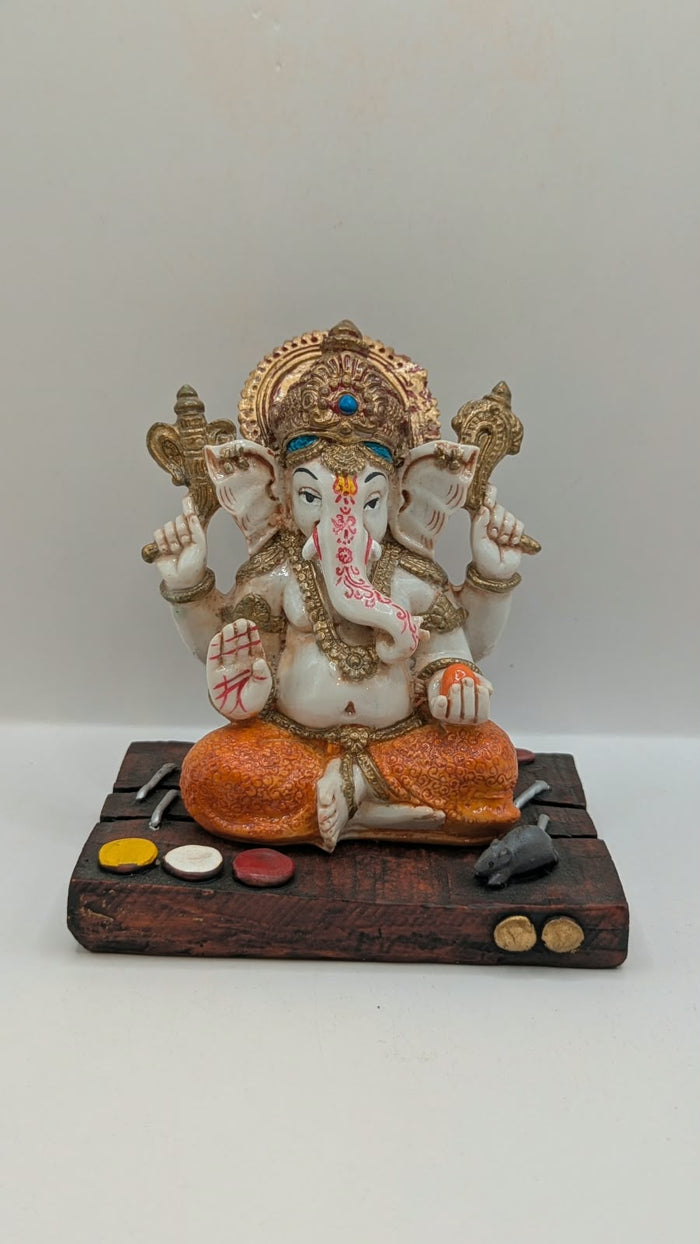 White and orange Ganesh resin statue on wood-look base, front view