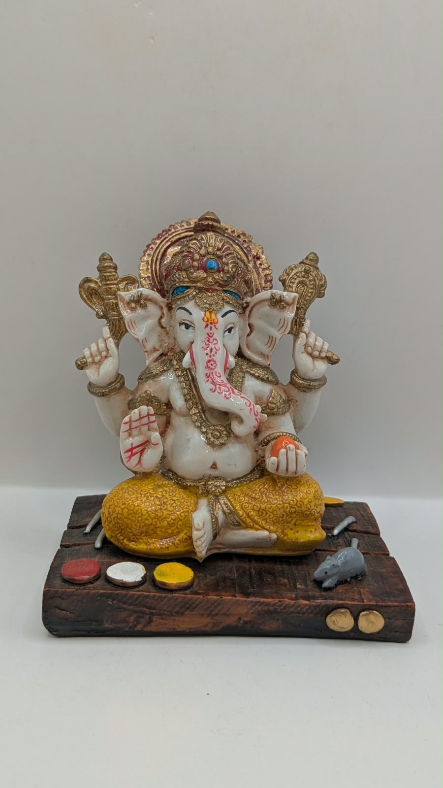White and yellow Ganesh resin statue on wood-look base, front view