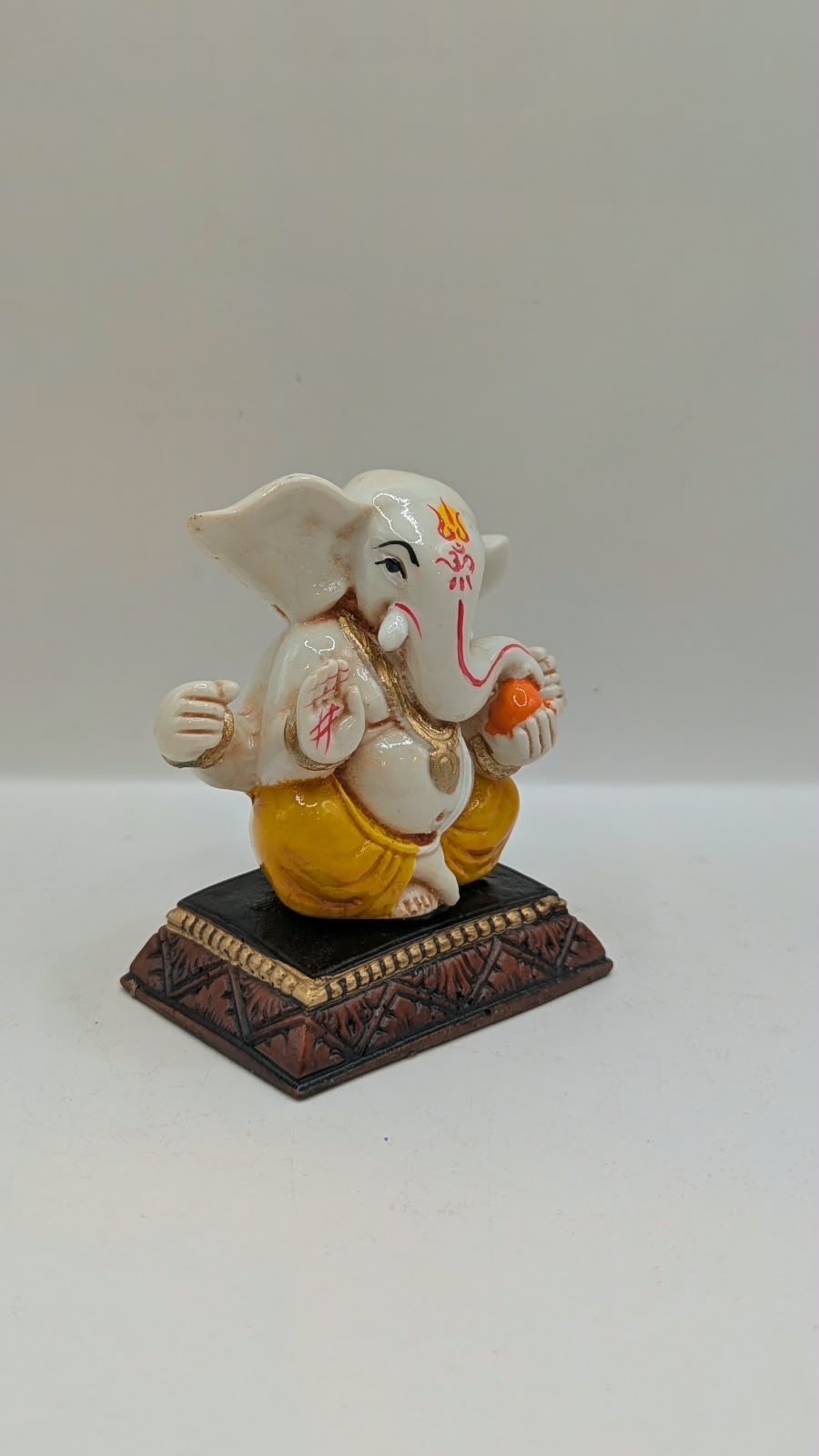White and yellow Ganesh resin statue, side view