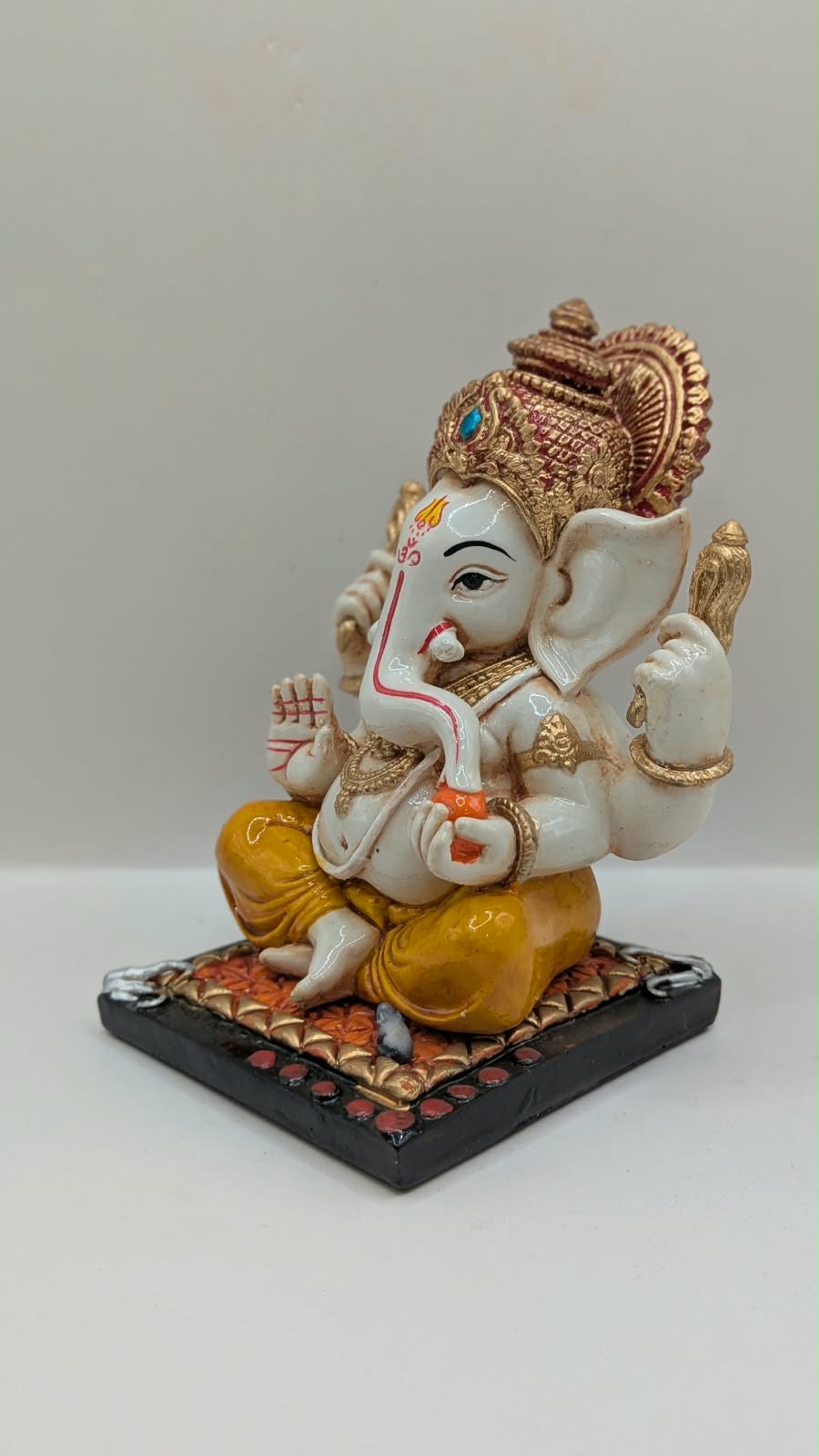 White and yellow Ganesh resin statue with copper crown, other side view
