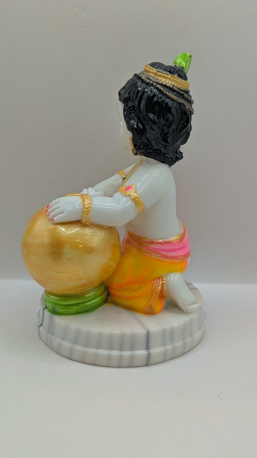 Baby Krishna statue hugging gold pot, back view