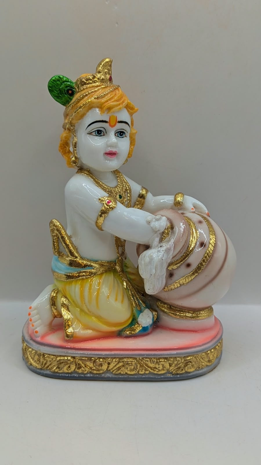 Baby Krishna statue with white pot, side view