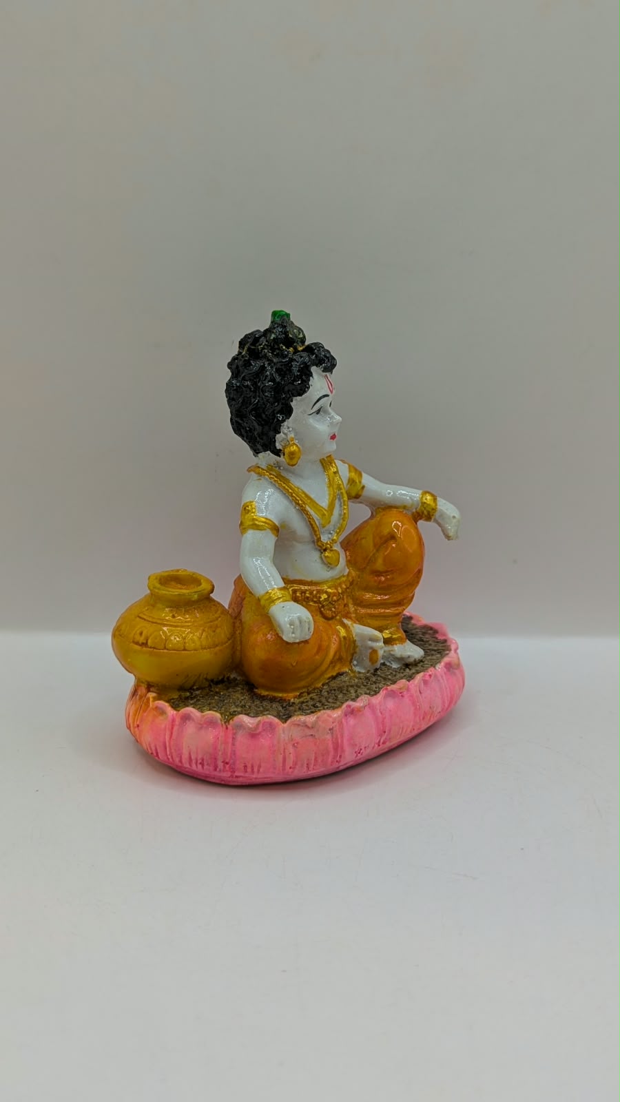 Baby Krishna statue on pink lotus, side view