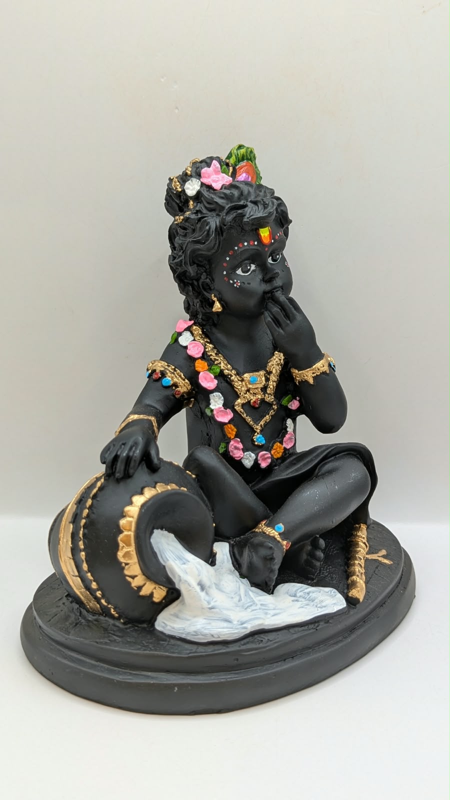 Black baby Krishna with butter pot, side view